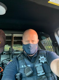a police officer wearing a face mask in his car